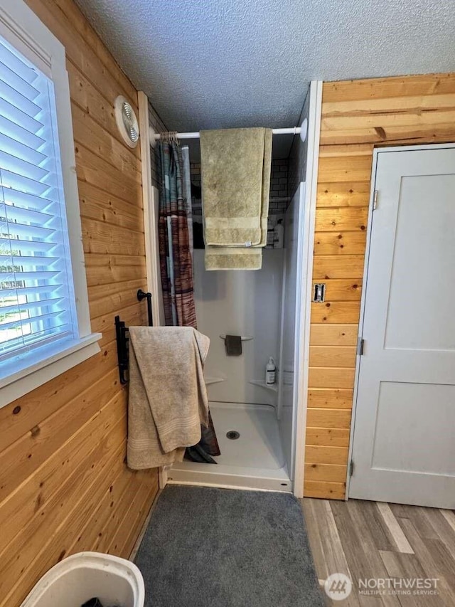 8839 Daffodil Ln SE, Olympia, WA 98513 - full bath featuring wood walls, a shower stall, a textured ceiling, and wood finished floors