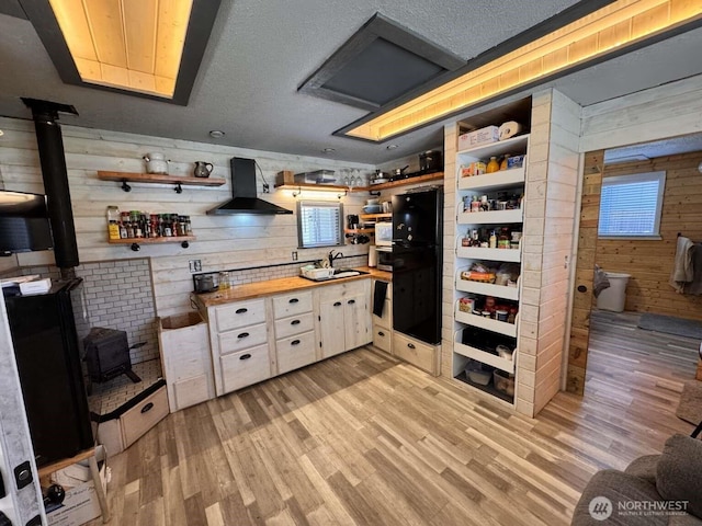 8839 Daffodil Ln SE, Olympia, WA 98513 - kitchen with open shelves, ventilation hood, a wood stove, butcher block countertops, and wooden walls