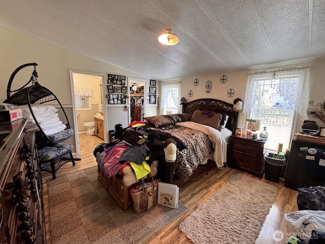 8839 Daffodil Ln SE, Olympia, WA 98513 - bedroom featuring wood finished floors, ensuite bath, lofted ceiling, and a textured ceiling