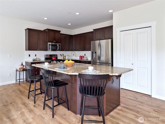 16271 SE 181st St, Renton, WA 98058 - kitchen featuring appliances with stainless steel finishes, light wood finished floors, decorative backsplash, dark brown cabinetry, and recessed lighting