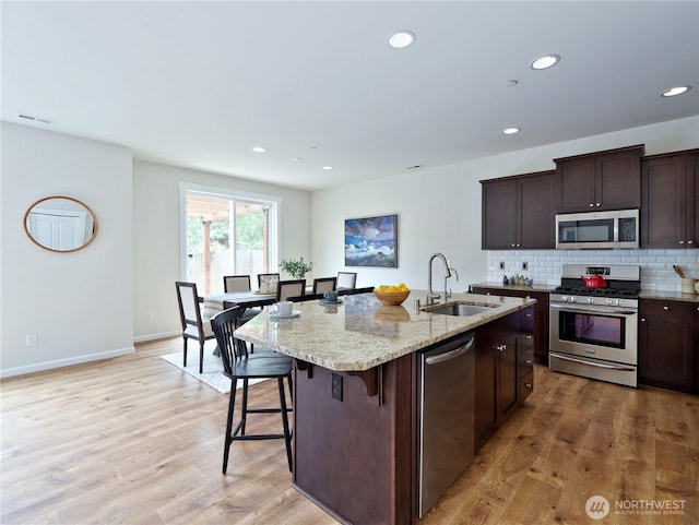 16271 SE 181st St, Renton, WA 98058 - kitchen featuring appliances with stainless steel finishes, recessed lighting, light stone countertops, an island with sink, and light wood-type flooring