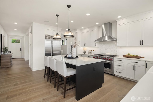 3865 46th Ave NE, Seattle, WA 98105 - kitchen featuring wall chimney exhaust hood, high end appliances, light countertops, backsplash, and light wood-type flooring