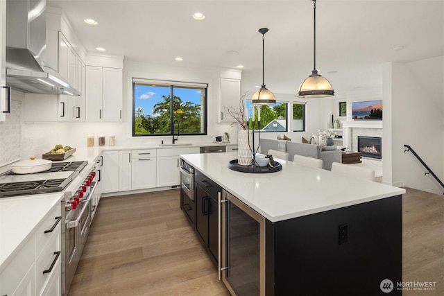 3865 46th Ave NE, Seattle, WA 98105 - kitchen featuring double oven range, beverage cooler, wall chimney exhaust hood, light wood-style floors, and a kitchen island