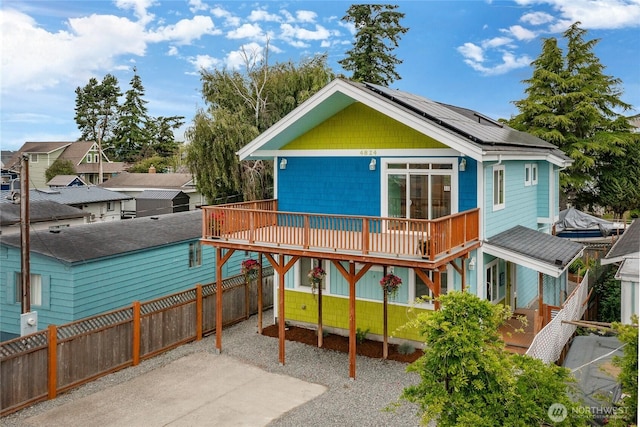 4824 Willow Dr, Blaine, WA 98230 - rear view of property with roof mounted solar panels, a fenced backyard, a wooden deck, a residential view, and gravel driveway
