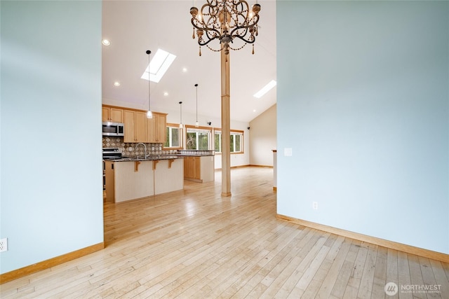 4824 Willow Dr, Blaine, WA 98230 - kitchen with stainless steel microwave, light brown cabinetry, a kitchen breakfast bar, tasteful backsplash, and a kitchen island with sink