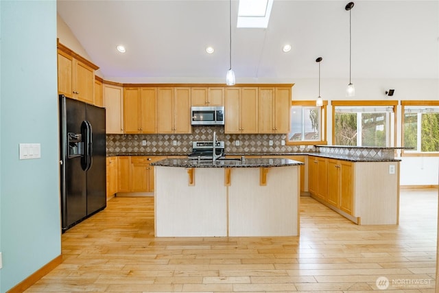 4824 Willow Dr, Blaine, WA 98230 - kitchen featuring appliances with stainless steel finishes, a kitchen bar, a peninsula, dark stone counters, and light wood finished floors