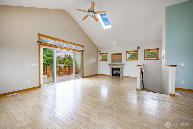 4824 Willow Dr, Blaine, WA 98230 - unfurnished living room with ceiling fan, high vaulted ceiling, hardwood / wood-style flooring, a glass covered fireplace, and a skylight
