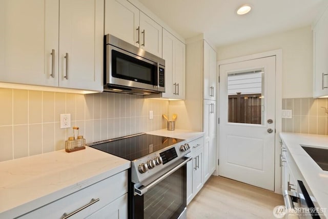 12302 5th Ave NE, Seattle, WA 98125 - kitchen featuring stainless steel appliances, decorative backsplash, light stone counters, light wood finished floors, and white cabinets