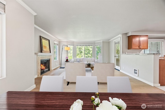 9822 NE 122nd St Unit U201, Kirkland, WA 98034 - dining room featuring ornamental molding, healthy amount of natural light, a tiled fireplace, and light wood-style flooring