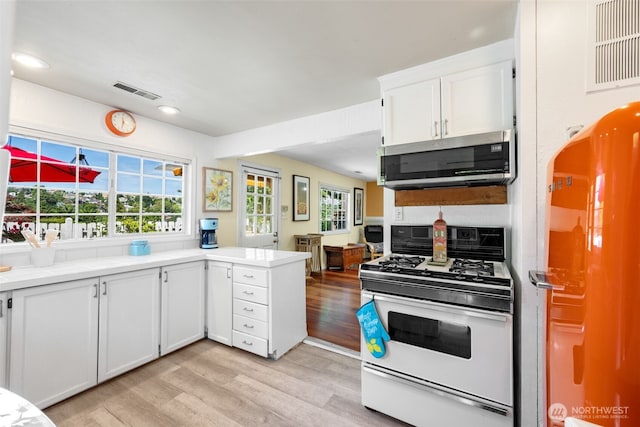 1524 30th Ave, Seattle, WA 98122 - kitchen featuring white gas range oven, stainless steel microwave, fridge, light wood finished floors, and light countertops