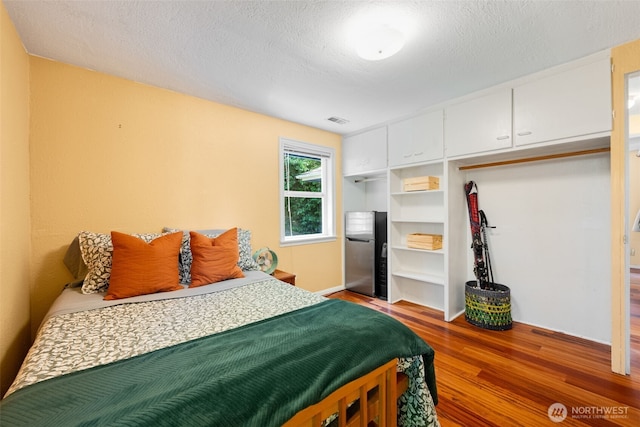1524 30th Ave, Seattle, WA 98122 - bedroom with freestanding refrigerator, wood finished floors, and a textured ceiling