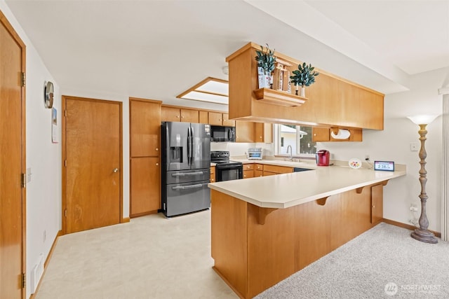 50 Steve Pl, Sequim, WA 98382 - kitchen featuring black appliances, a peninsula, light countertops, a kitchen breakfast bar, and brown cabinets