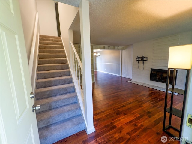 1717 150th Ave SE Unit 31, Bellevue, WA 98007 - staircase with wood finished floors, a textured ceiling, and a large fireplace