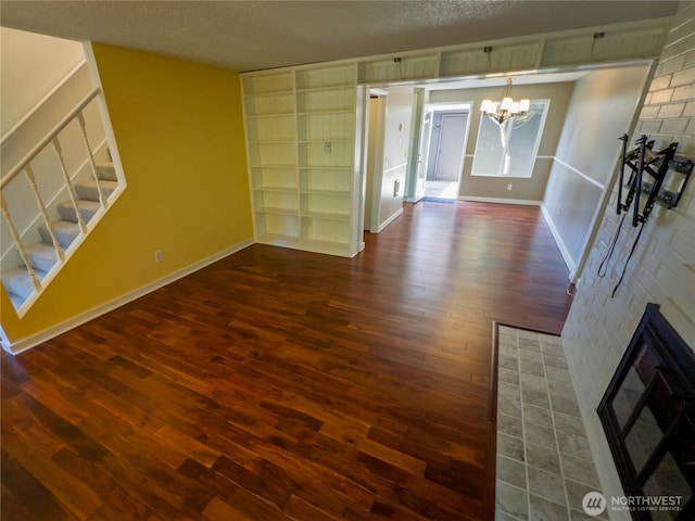 1717 150th Ave SE Unit 31, Bellevue, WA 98007 - unfurnished living room with a chandelier, dark wood-style floors, a glass covered fireplace, and a textured ceiling