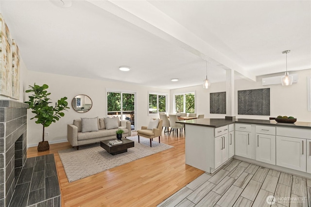 10032 35th Ave NE, Seattle, WA 98125 - kitchen featuring light wood finished floors, a tile fireplace, dark countertops, open floor plan, and pendant lighting
