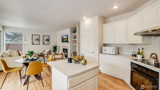 17303 SE 185th St, Renton, WA 98058 - kitchen with black appliances, under cabinet range hood, light wood finished floors, a kitchen island, and white cabinetry