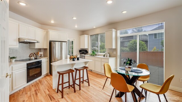 17303 SE 185th St, Renton, WA 98058 - kitchen featuring black appliances, under cabinet range hood, a kitchen island, tasteful backsplash, and white cabinetry