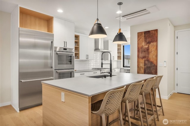 330 3rd Ave S Unit C, Kirkland, WA 98033 - kitchen featuring stainless steel appliances, open shelves, wall chimney range hood, backsplash, and light wood-style flooring