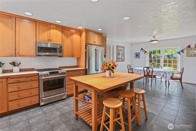 541 75th Way NE, Olympia, WA 98506 - kitchen with appliances with stainless steel finishes, brown cabinetry, light countertops, recessed lighting, and a textured ceiling