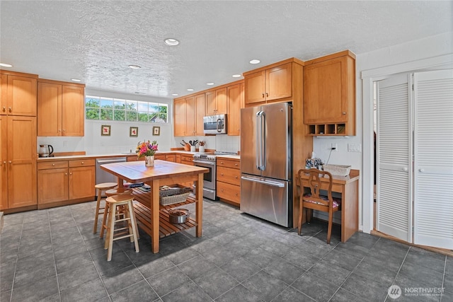 541 75th Way NE, Olympia, WA 98506 - kitchen featuring stainless steel appliances, recessed lighting, light countertops, a textured ceiling, and brown cabinetry