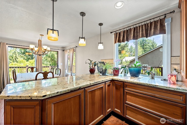 21410 SE 265th Pl, Maple Valley, WA 98038 - kitchen with brown cabinets, healthy amount of natural light, a chandelier, and light stone countertops