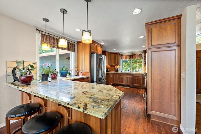 21410 SE 265th Pl, Maple Valley, WA 98038 - kitchen featuring stainless steel fridge, a peninsula, brown cabinetry, light stone countertops, and recessed lighting