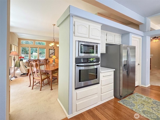 77 A Rd, Less Traveled, Sequim, WA 98382 - kitchen featuring appliances with stainless steel finishes, white cabinets, light countertops, wood finished floors, and decorative light fixtures