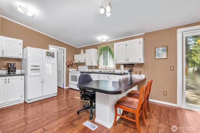 8310 207th St E, Spanaway, WA 98387 - kitchen with white appliances, dark countertops, vaulted ceiling, a kitchen breakfast bar, and crown molding