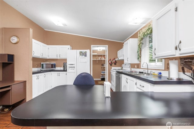 8310 207th St E, Spanaway, WA 98387 - kitchen with white appliances, lofted ceiling, crown molding, dark countertops, and white cabinets