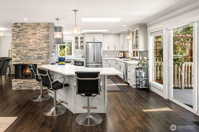 16671 SE 17th Pl, Bellevue, WA 98008 - kitchen with stainless steel appliances, light countertops, a kitchen bar, tasteful backsplash, and glass insert cabinets