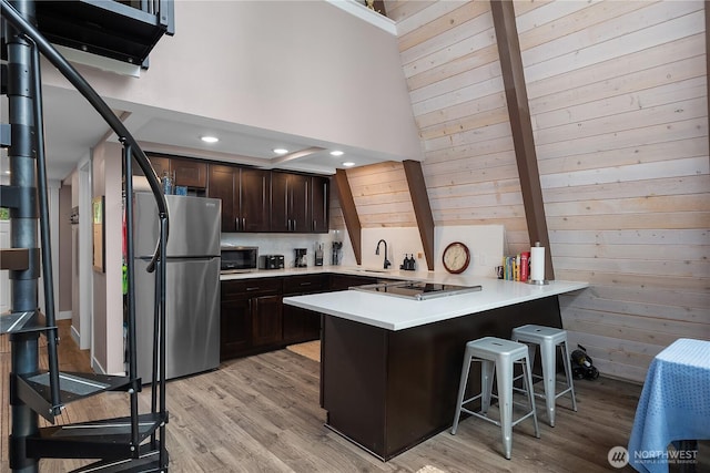 22305 Autumnwood Ct SE, Yelm, WA 98597 - kitchen featuring stainless steel appliances, a peninsula, dark brown cabinets, a kitchen breakfast bar, and light countertops