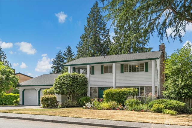 1023 144th Pl SE, Bellevue, WA 98007 - view of front facade featuring a chimney, an attached garage, driveway, and brick siding