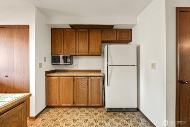 110 Icicle Unit K, Leavenworth, WA 98826 - kitchen featuring freestanding refrigerator, tile counters, black microwave, and brown cabinets
