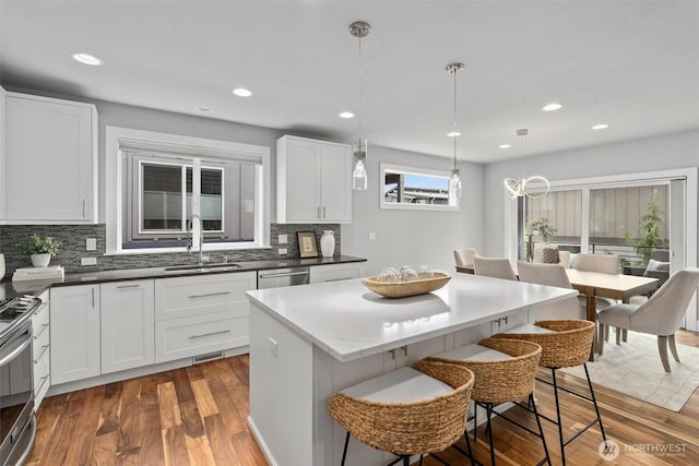 9909 123rd Ln NE, Kirkland, WA 98033 - kitchen featuring appliances with stainless steel finishes, a breakfast bar area, tasteful backsplash, dark wood-style floors, and recessed lighting