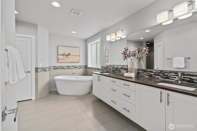 9909 123rd Ln NE, Kirkland, WA 98033 - bathroom featuring double vanity, a freestanding tub, recessed lighting, and a wainscoted wall
