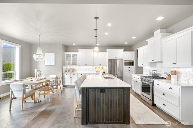 1312 Bradley Meadows Ct, Lynden, WA 98263 - kitchen featuring appliances with stainless steel finishes, decorative backsplash, white cabinetry, a kitchen island with sink, and light countertops
