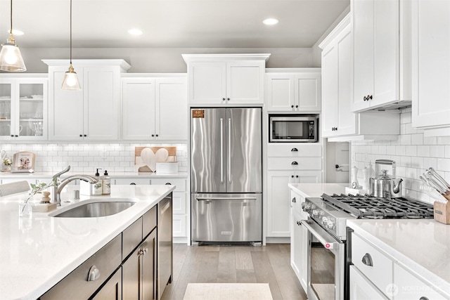 1312 Bradley Meadows Ct, Lynden, WA 98263 - kitchen with stainless steel appliances, light countertops, white cabinets, light wood-style floors, and hanging light fixtures