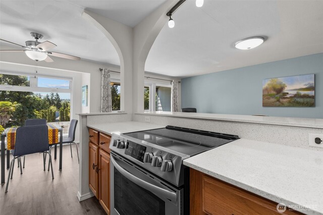 15152 65th Ave S Unit 818, Tukwila, WA 98188 - kitchen featuring stainless steel range with electric stovetop, brown cabinetry, plenty of natural light, and wood finished floors