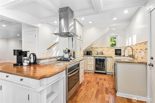 3915 Gilmore Rd, Everson, WA 98247 - kitchen featuring wall chimney range hood, oven, light wood finished floors, wine cooler, and decorative backsplash