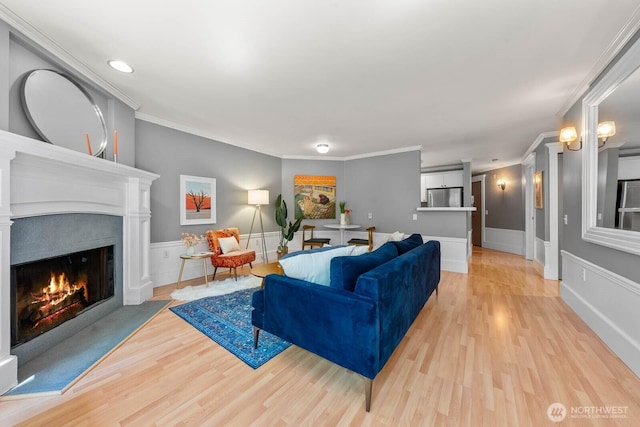 727 N 85th St Unit 102, Seattle, WA 98103 - living area featuring crown molding, light wood-type flooring, a warm lit fireplace, and wainscoting