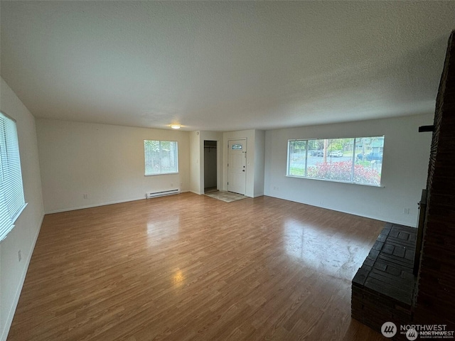 16425 Broadway Ave, Snohomish, WA 98296 - unfurnished living room featuring a baseboard heating unit, wood finished floors, healthy amount of natural light, and a textured ceiling