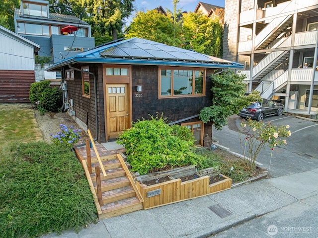 3522 S Leschi Pl, Seattle, WA 98144 - property entrance with roof mounted solar panels, a metal roof, a standing seam roof, and uncovered parking