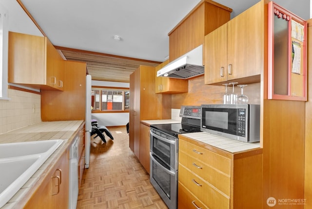 3522 S Leschi Pl, Seattle, WA 98144 - kitchen with appliances with stainless steel finishes, under cabinet range hood, tile countertops, and decorative backsplash