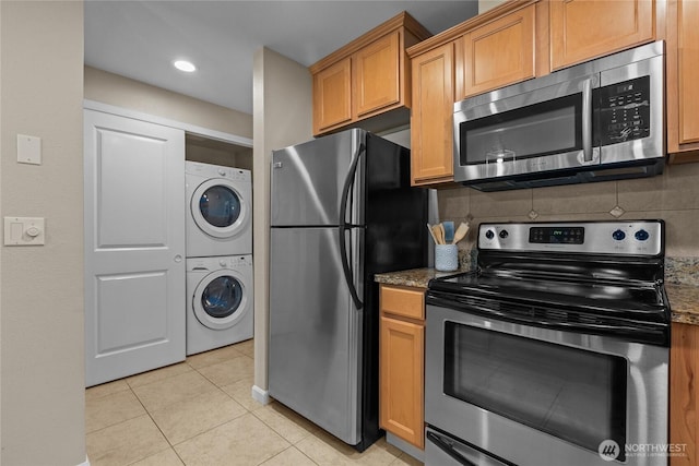 1302 N 6th St Unit 8, Tacoma, WA 98403 - kitchen with stainless steel appliances, stacked washing machine and dryer, light tile patterned floors, stone countertops, and backsplash