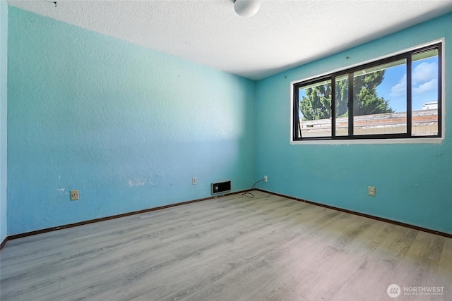 9404 Stone Ave N, Seattle, WA 98103 - spare room featuring wood finished floors, a textured ceiling, and a textured wall