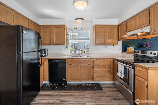 1949 S Sheridan Ave, Tacoma, WA 98405 - kitchen with black appliances, under cabinet range hood, dark wood-style floors, light countertops, and brown cabinetry