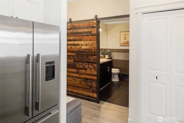 530 4th Ave W Unit 405, Seattle, WA 98119 - kitchen with stainless steel fridge, light wood-type flooring, tile walls, and wainscoting