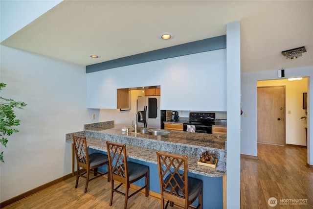 140 Admiralty Ln Unit 370, Port Ludlow, WA 98365 - kitchen with electric range, wood finished floors, a breakfast bar area, stainless steel fridge, and recessed lighting