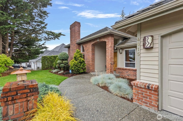 4015 E Broadway St, Mount Vernon, WA 98274 - view of exterior entry featuring brick siding, a chimney, a garage, and a yard