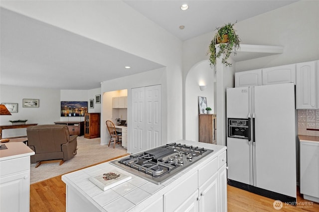 4015 E Broadway St, Mount Vernon, WA 98274 - kitchen featuring white fridge with ice dispenser, stainless steel gas cooktop, tile counters, arched walkways, and open floor plan